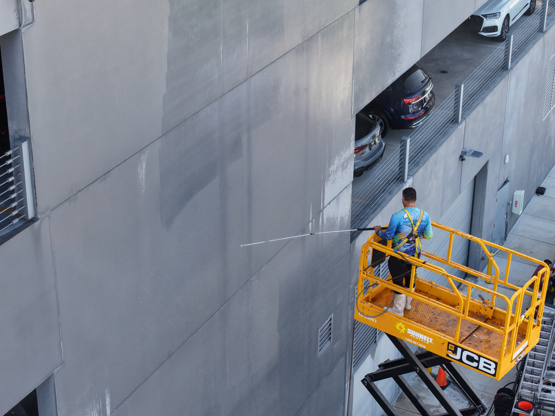 Commercial building exterior pressure cleaning from scissor lift in Hialeah FL