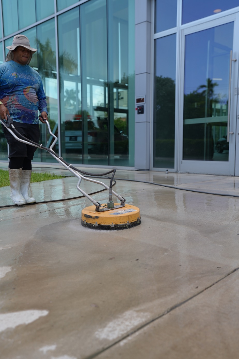 Worker pressure cleaning commercial building entrance in Hialeah FL