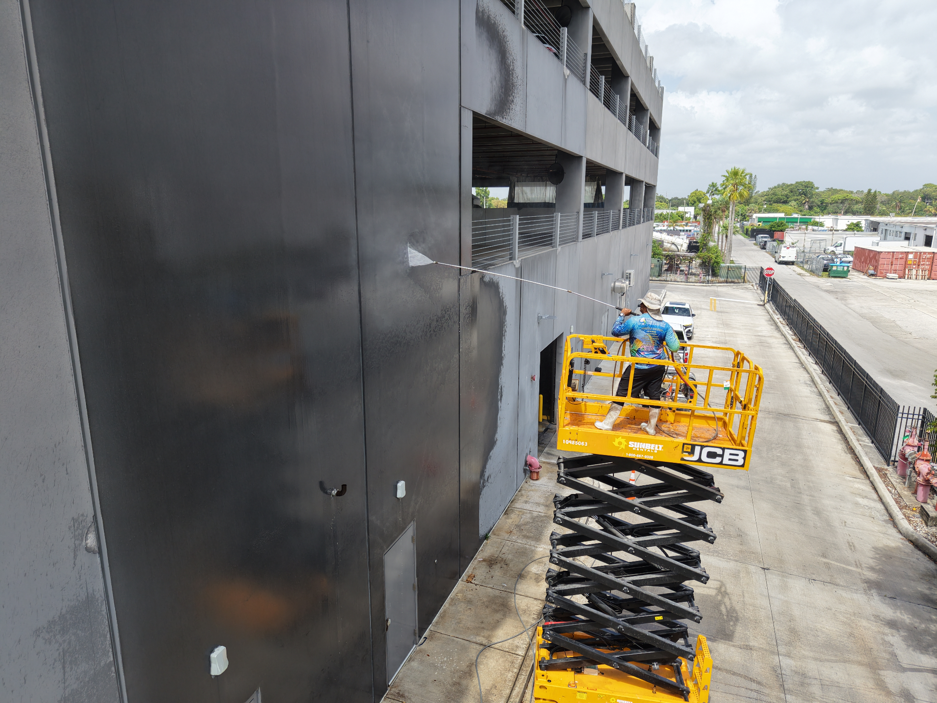 Pressure washing parking garage wall from scissor lift in Hialeah FL