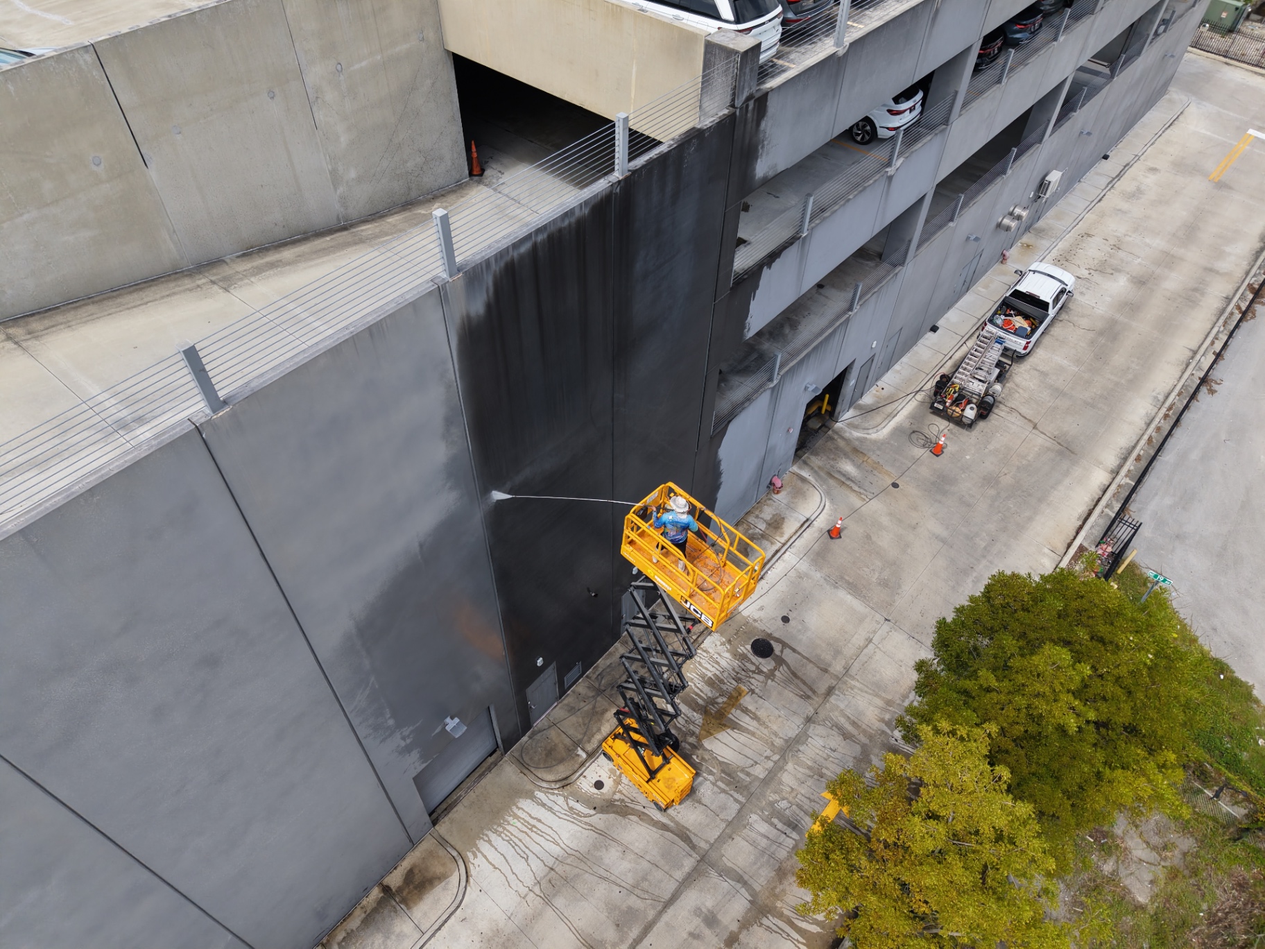 Worker cleaning parking garage facade from lift in Hialeah FL